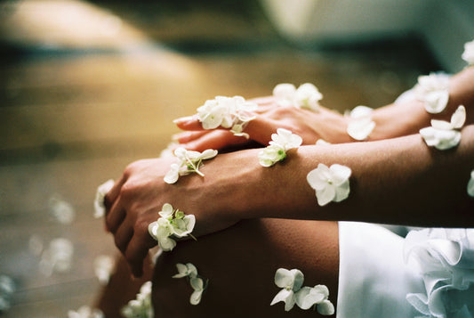 a woman sitting with many white flowers on her arm